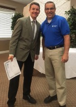 Two men smiling, one holding a diploma